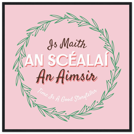 Irish proverb Is Maith an Scéalaí an Aimsir in a green leaf wreath on pink, black framed print
