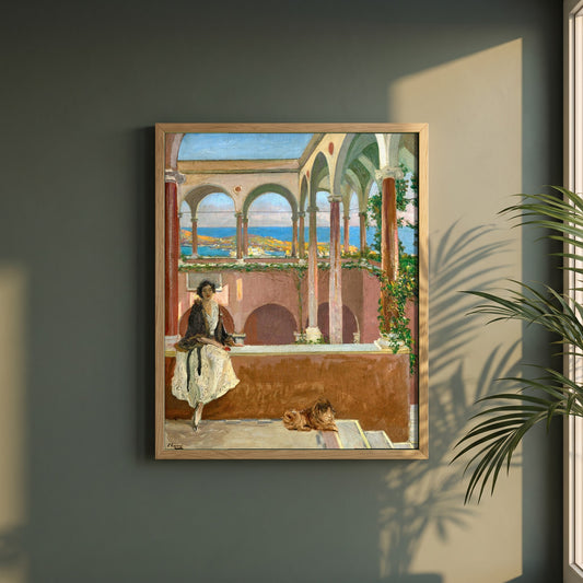 A Villa on the Riviera framed print in a natural oak frame on a dark green wall beside a window, dappled plant shadow
