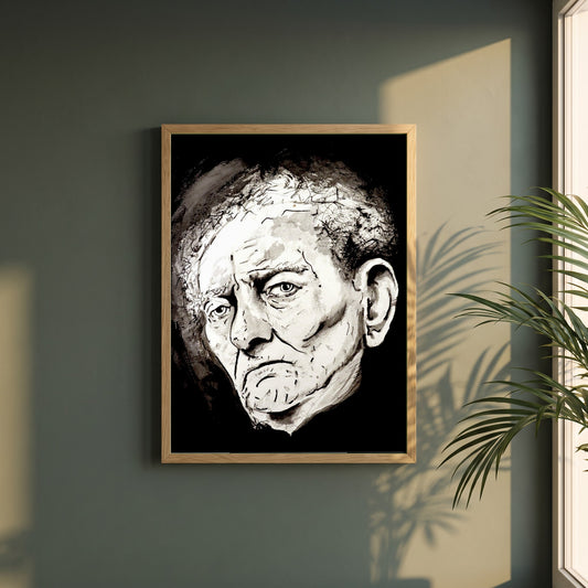 Brian Friel framed print in a natural oak frame on a dark green wall beside a window, dappled plant shadow