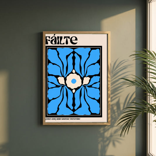 Fáilte framed print in a natural oak frame on a dark green wall beside a window, dappled plant shadow