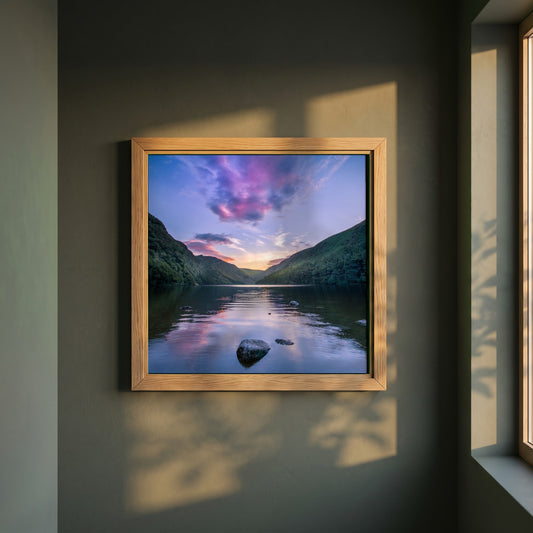 Glendalough Lake Art Print, County Wicklow framed print in a natural oak frame on a dark green wall beside a window, dappled plant shadow