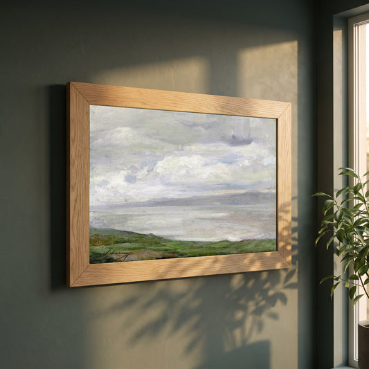 Island Magee framed print in a natural oak frame on a dark green wall beside a window, dappled plant shadow