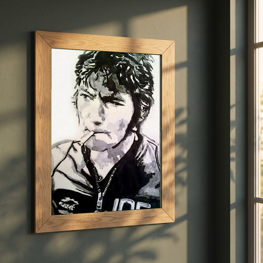 Joey Dunlop framed print in a natural oak frame on a dark green wall beside a window, dappled plant shadow