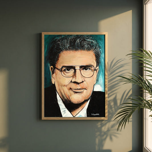 John Hume framed print in a natural oak frame on a dark green wall beside a window, dappled plant shadow
