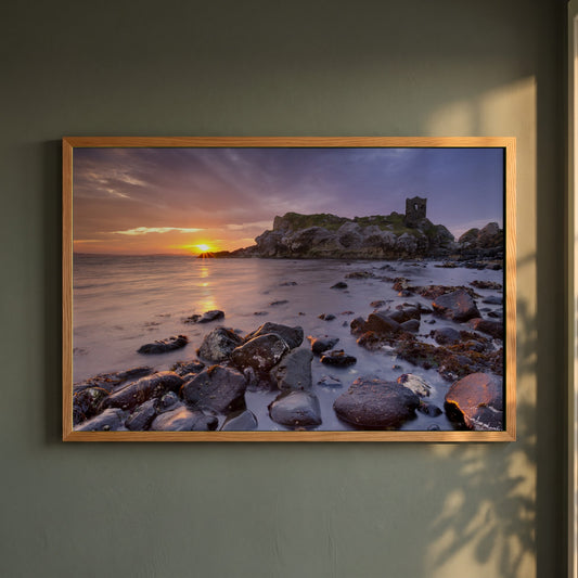 Kinbane Castle Ireland Photography framed print in a natural oak frame on a dark green wall beside a window, dappled plant shadow
