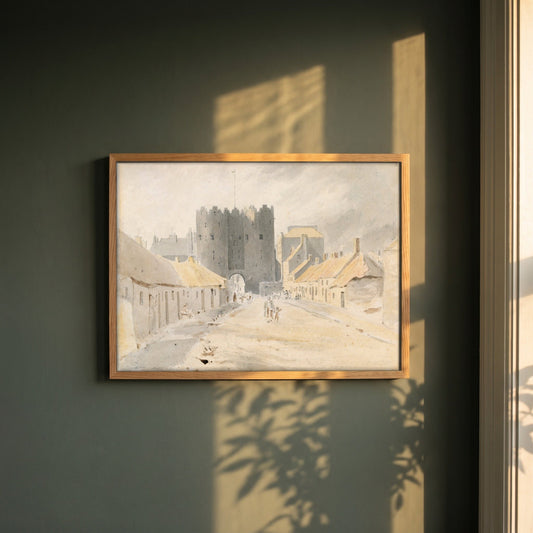 Saint Lawrence's Gate, Drogheda (1819) framed print in a natural oak frame on a dark green wall beside a window, dappled plant shadow
