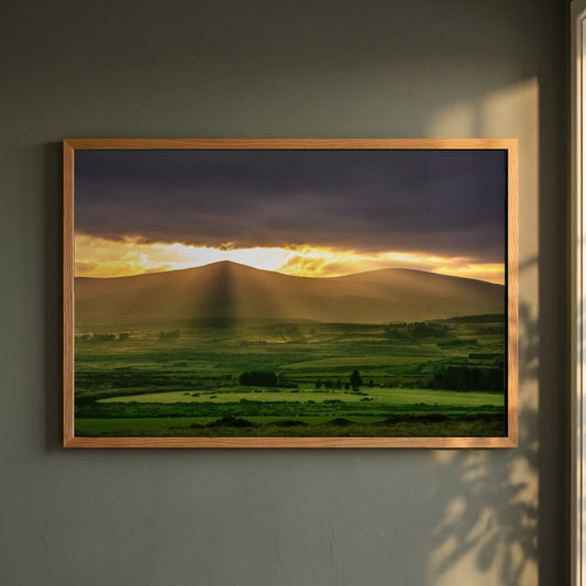 Sugarloaf Mountain, Wicklow framed print in a natural oak frame on a dark green wall beside a window, dappled plant shadow
