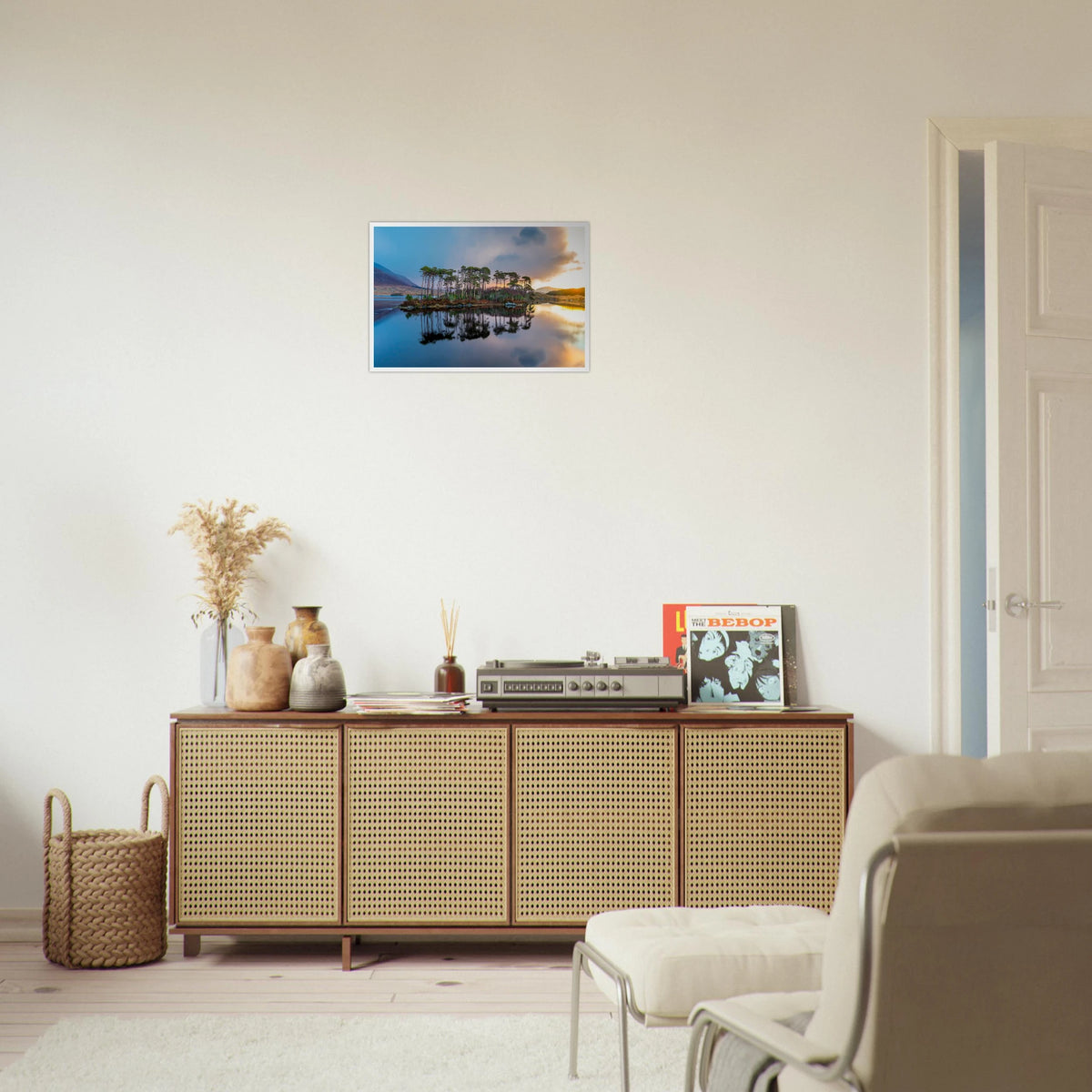 Twelve Pines Connemara lake photo print above a rattan sideboard with a record player