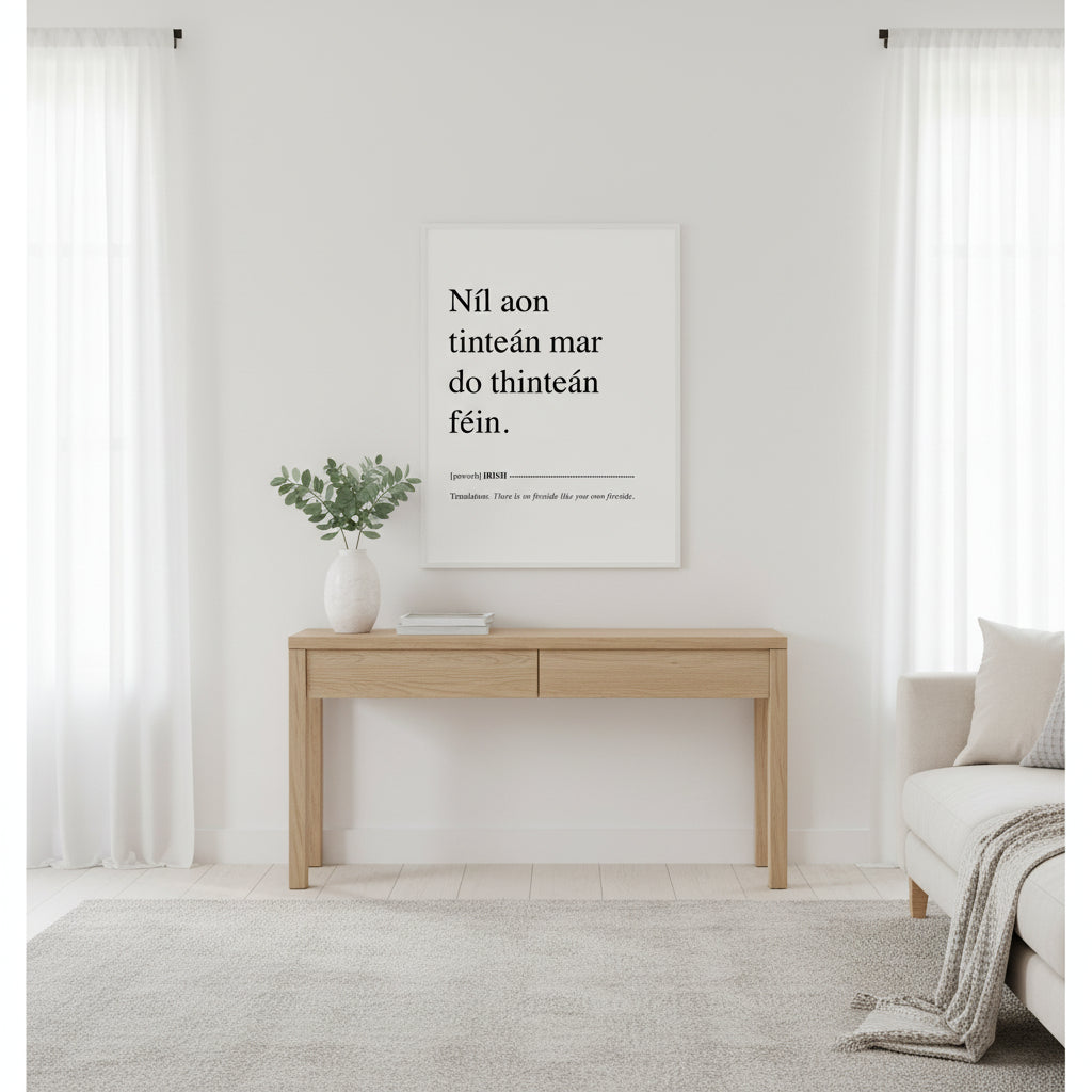 Níl aon tinteán mar do thinteán féin. Translation: There Is No Fireside Like Your Own Fireside. This Irish language framed print makes a great present, birthday gift and ideal Irish housewarming gift, or for Gaelic speakers. Irish proverb print ‘Níl aon tinteán mar do thinteán féin’ in a white gallery frame, bright Scandi living room, white walls, pale oak console, ceramic vase with eucalyptus, diffused daylight, clean magazine aesthetic.”