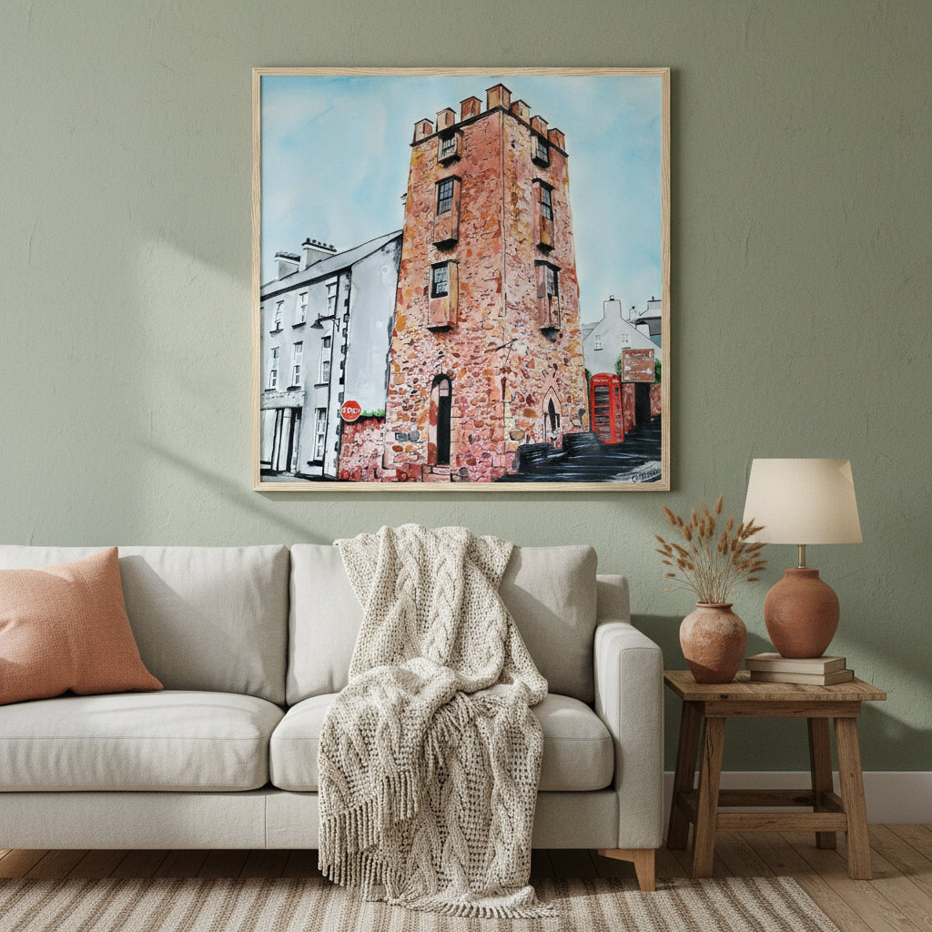 Large 70×70 cm natural oak-framed art print of The Curfew Tower Cushendall displayed in a warm Irish-inspired home interior, muted earthy palette, soft lamplight ambience, premium lifestyle photography highlighting frame texture and artwork detail.”Framed art print 'The Curfew Tower' by Ó Maoláin. This piece depicts The Curfew Tower in Cushendall, Glens of Antrim, built by Francis Turnley in 1820 and now owned by Bill Drummond. The artwork showcases the tower amid the scenic Glens of Antrim.