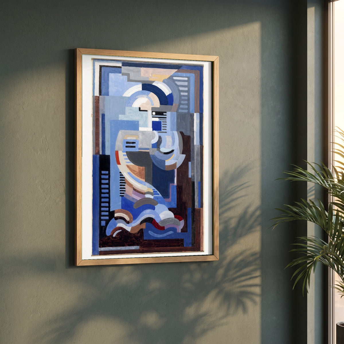 Abstract Blue Composition framed print in a natural oak frame on a dark green wall beside a window, dappled plant shadow