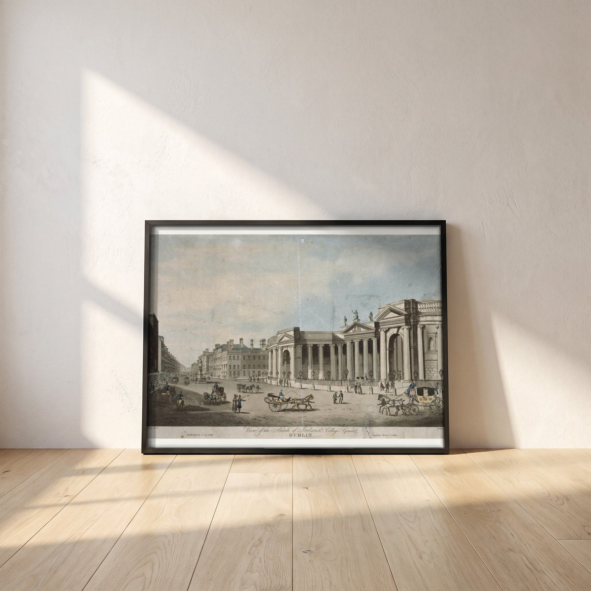 Bank of Ireland, College Green framed print in a black frame leaning against a white plaster wall on oak floorboards in morning light