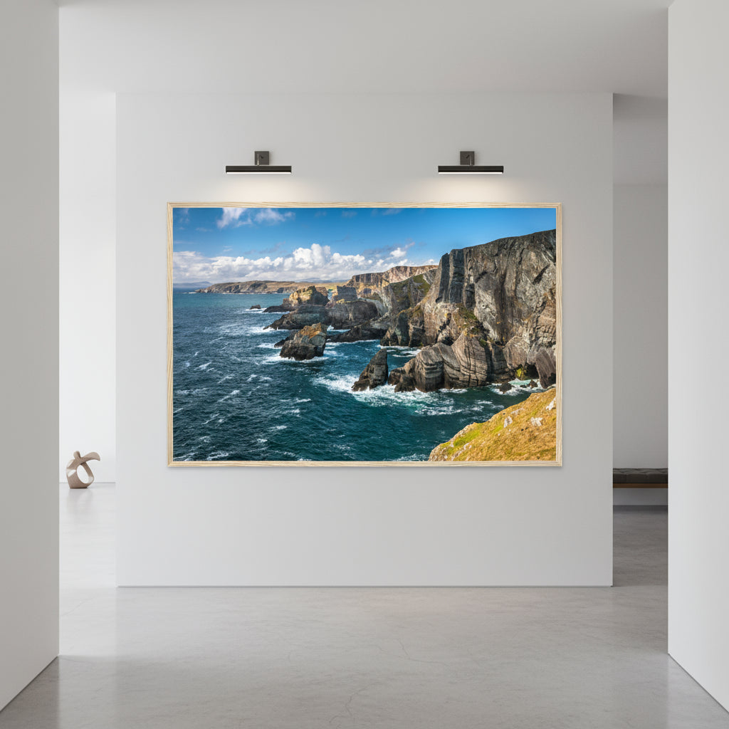 Mizen Head print in a light wood frame lit by wall lamps in a white hallway with a concrete floor
