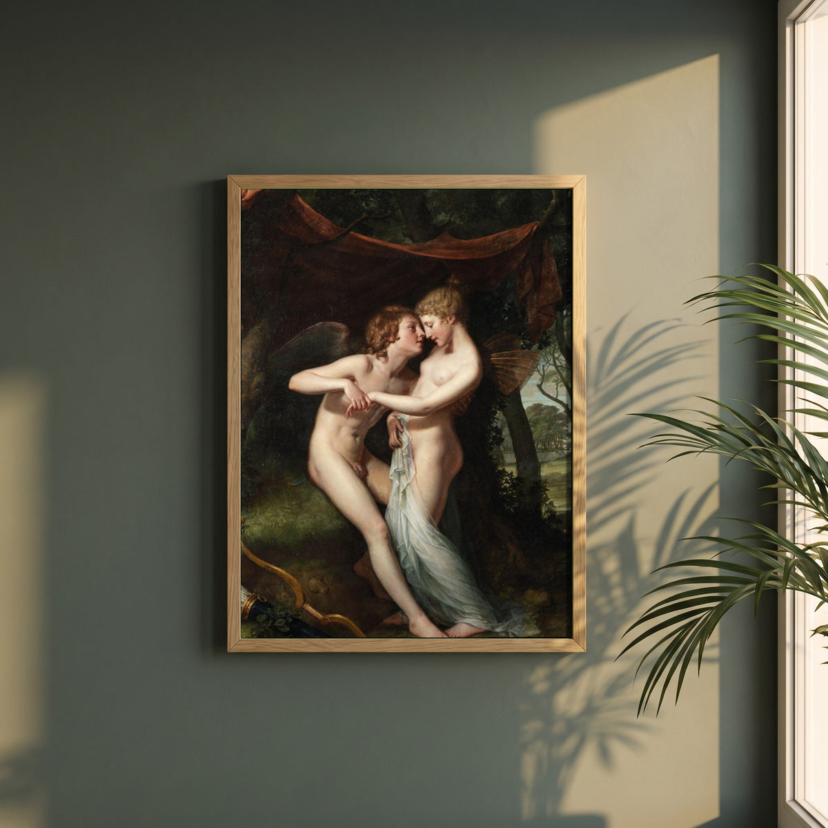 Cupid and Psyche framed print in a natural oak frame on a dark green wall beside a window, dappled plant shadow