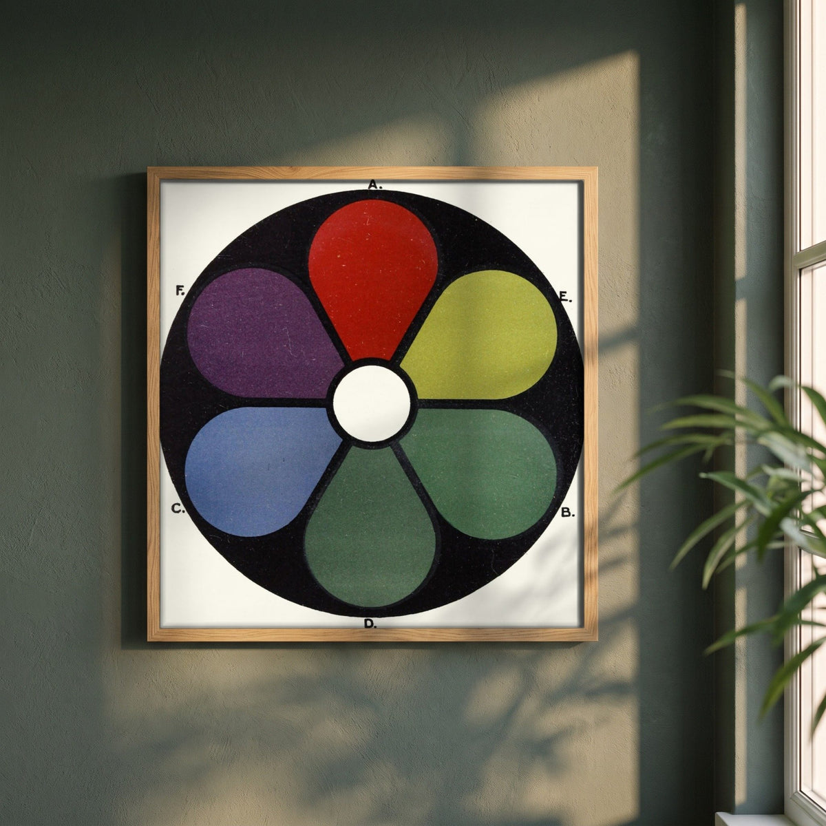 Darkened Shades of the Primaries by James Ward framed print in a natural oak frame on a dark green wall beside a window, dappled plant shadow