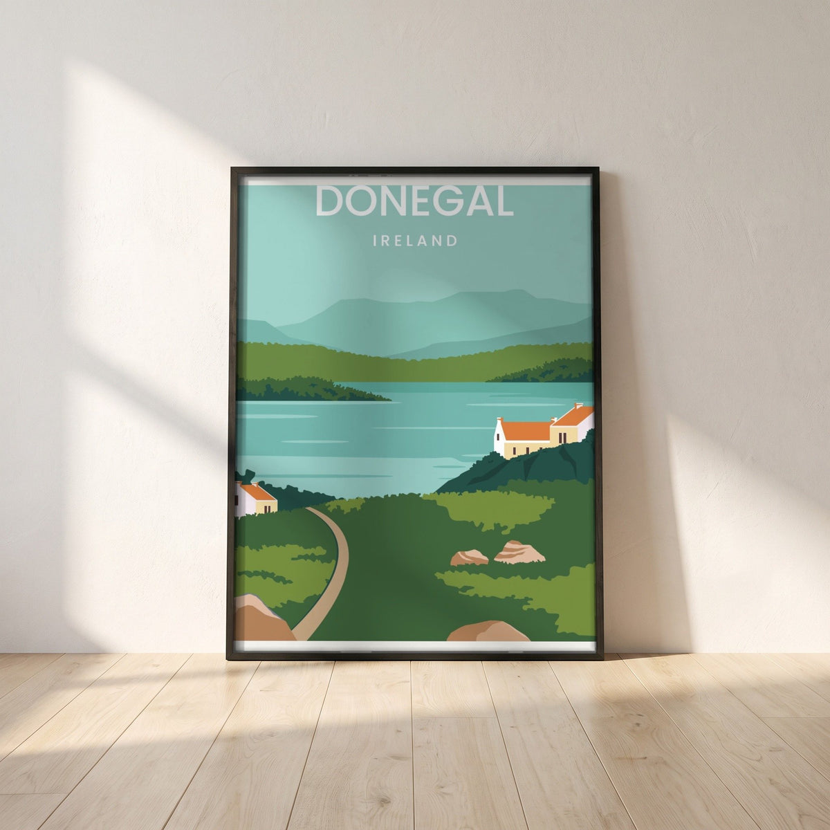 Donegal minimalist travel print in a black frame leaning against a white plaster wall on oak floorboards in morning light