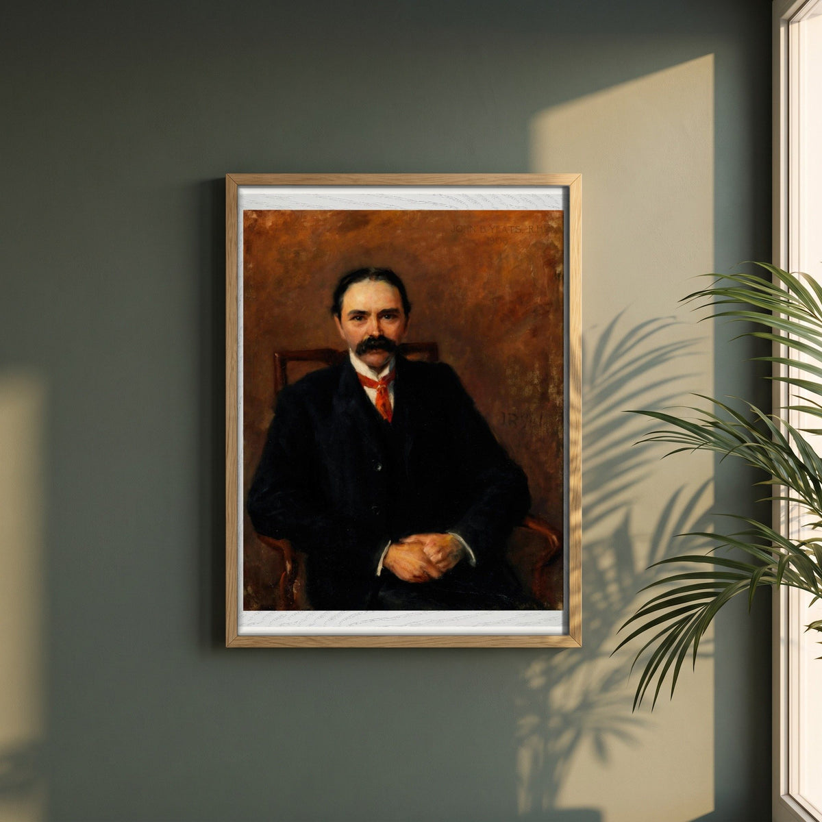 Douglas Hyde framed print in a natural oak frame on a dark green wall beside a window, dappled plant shadow