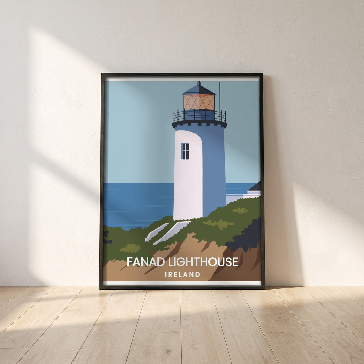 Fanad Head Lighthouse framed print in a black frame leaning against a white plaster wall on oak floorboards in morning light