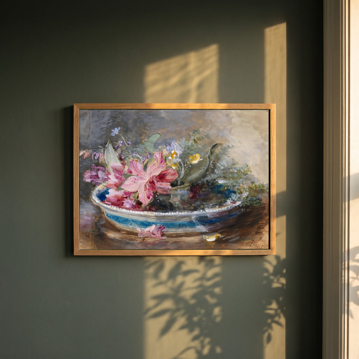 Flowers in a Bowl framed print in a natural oak frame on a dark green wall beside a window, dappled plant shadow
