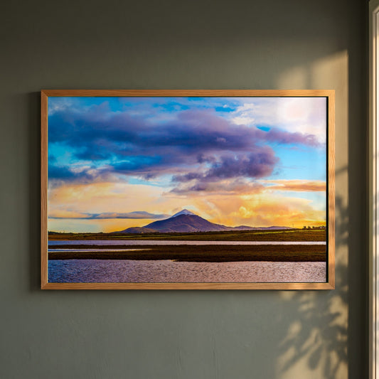 Croagh Patrick, Ireland framed print in a natural oak frame on a dark green wall beside a window, dappled plant shadow