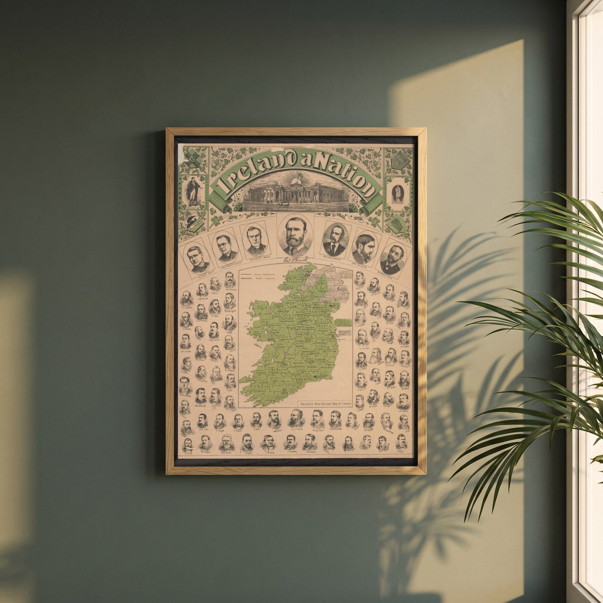 Ireland a Nation, Parnell's National Map of Ireland framed print in a natural oak frame on a dark green wall beside a window, dappled plant shadow