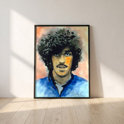 Phil Lynott Thin Lizzy framed print in a black frame leaning against a white plaster wall on oak floorboards in morning light