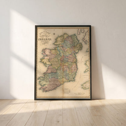 Map of Ireland framed print in a black frame leaning against a white plaster wall on oak floorboards in morning light