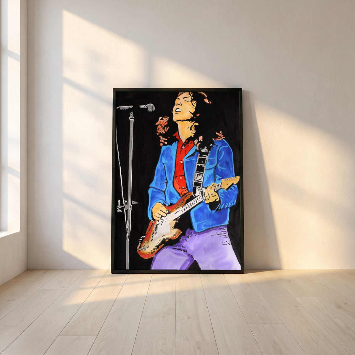 Rory Gallagher framed print in a black frame leaning against a white plaster wall on oak floorboards in morning light