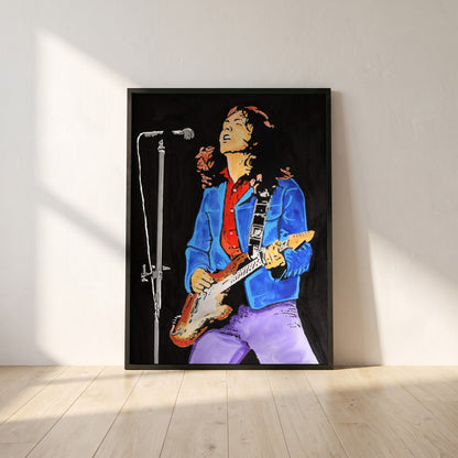 Rory Gallagher framed print in a black frame leaning against a white plaster wall on oak floorboards in morning light