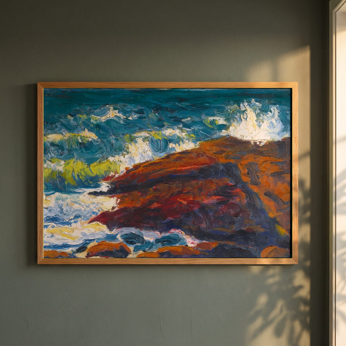 Seascape framed print in a natural oak frame on a dark green wall beside a window, dappled plant shadow